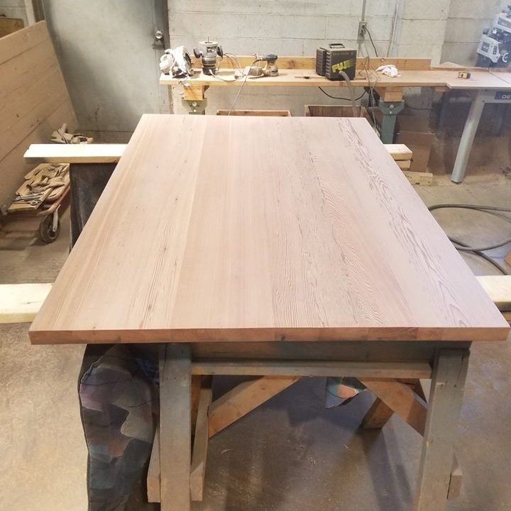 A repurposed wooden table is sitting in a room next to a workbench