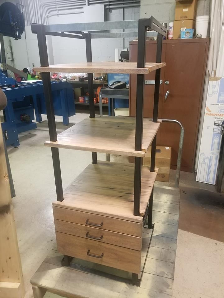 A wooden shelf with drawers is sitting on a cart in a room.