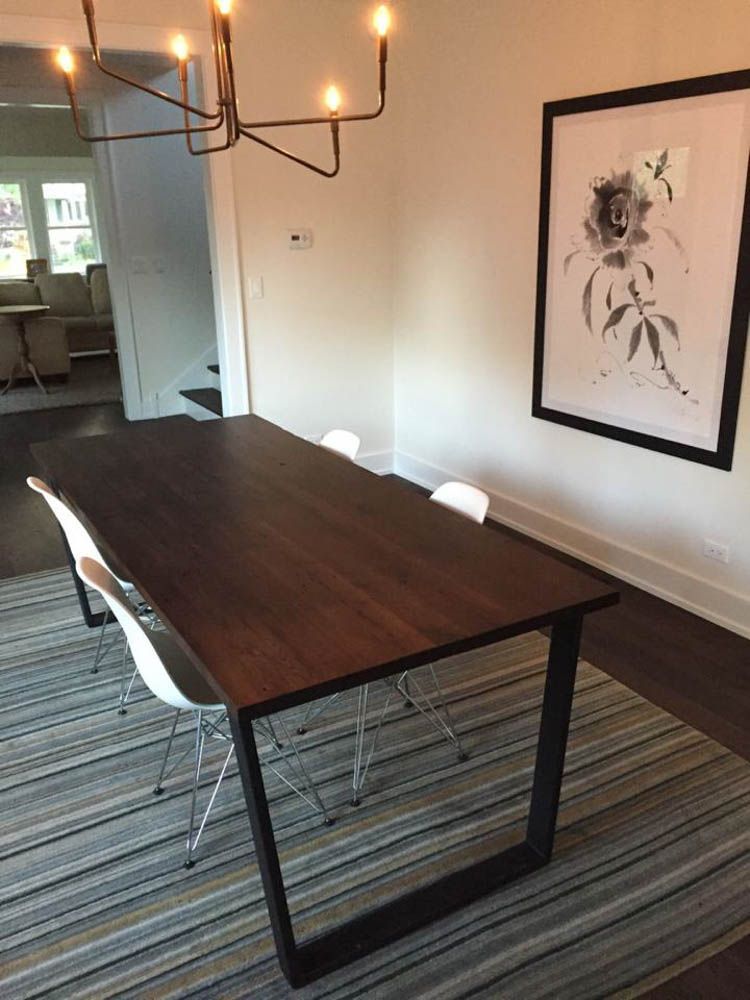 A dining room with a table and chairs and a picture on the wall.