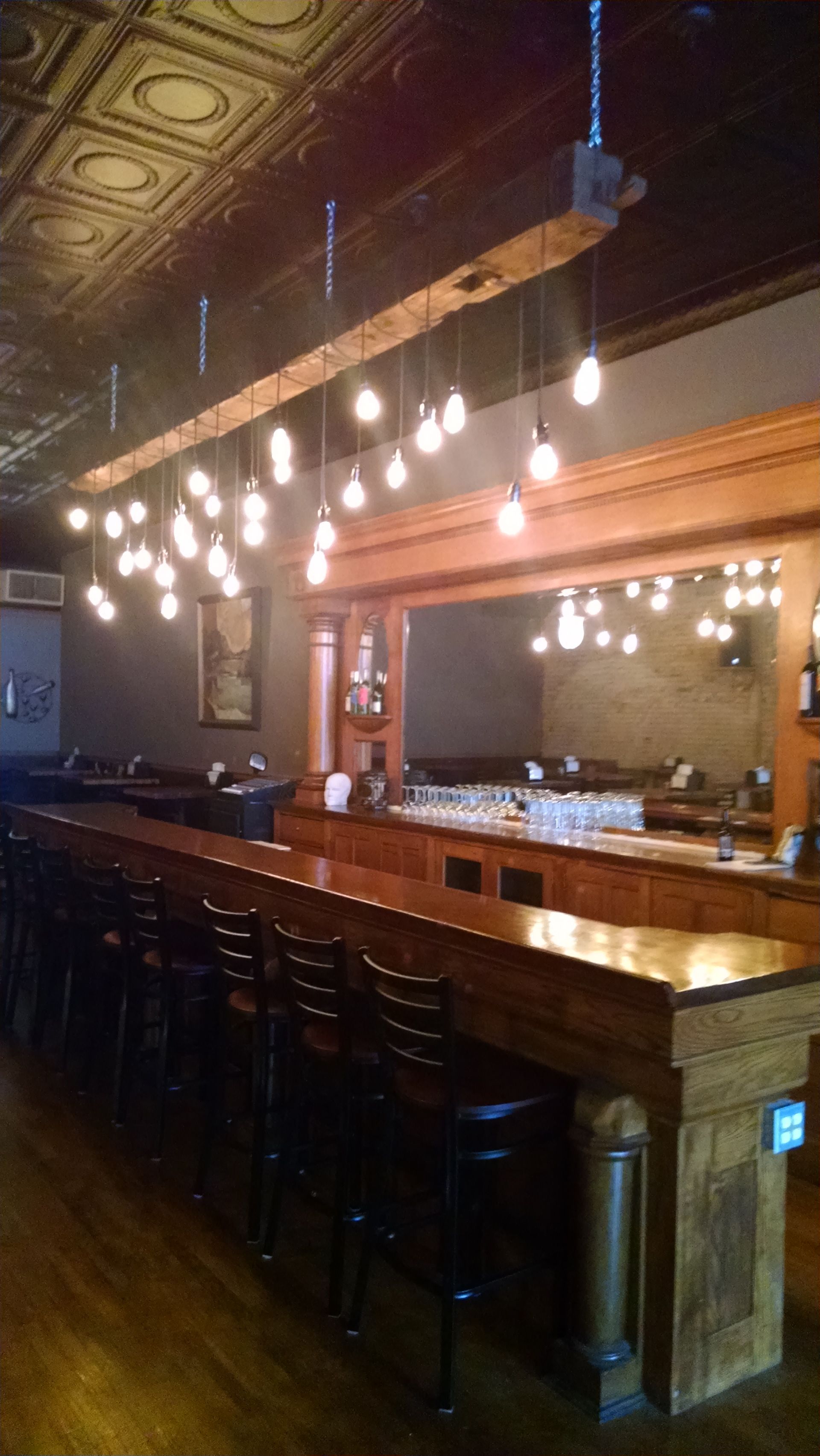 A long bar with a lot of lights hanging from the ceiling