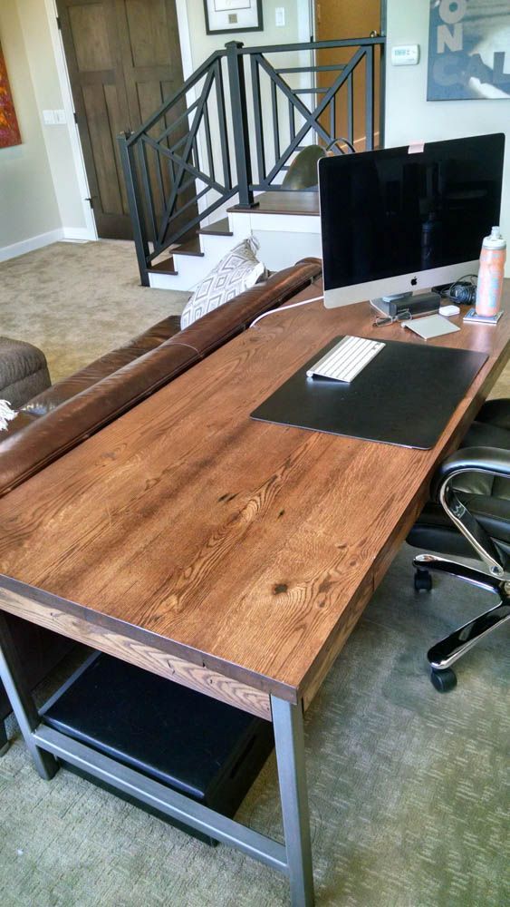 A wooden desk with a computer on it in a living room.