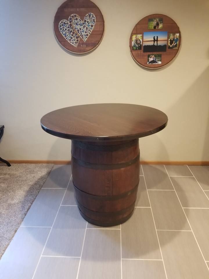 A custom wooden barrel table is sitting on a tiled floor in a room.