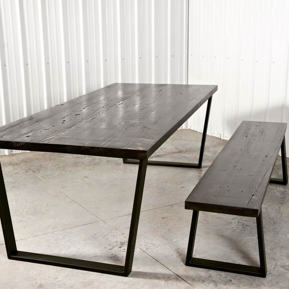 A wooden table with a metal frame and a bench next to it.