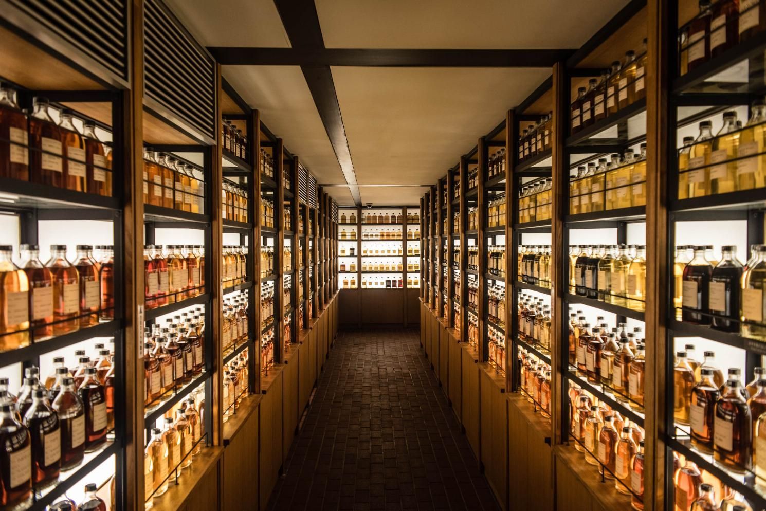 A long hallway filled with lots of bottles of alcohol on shelves.