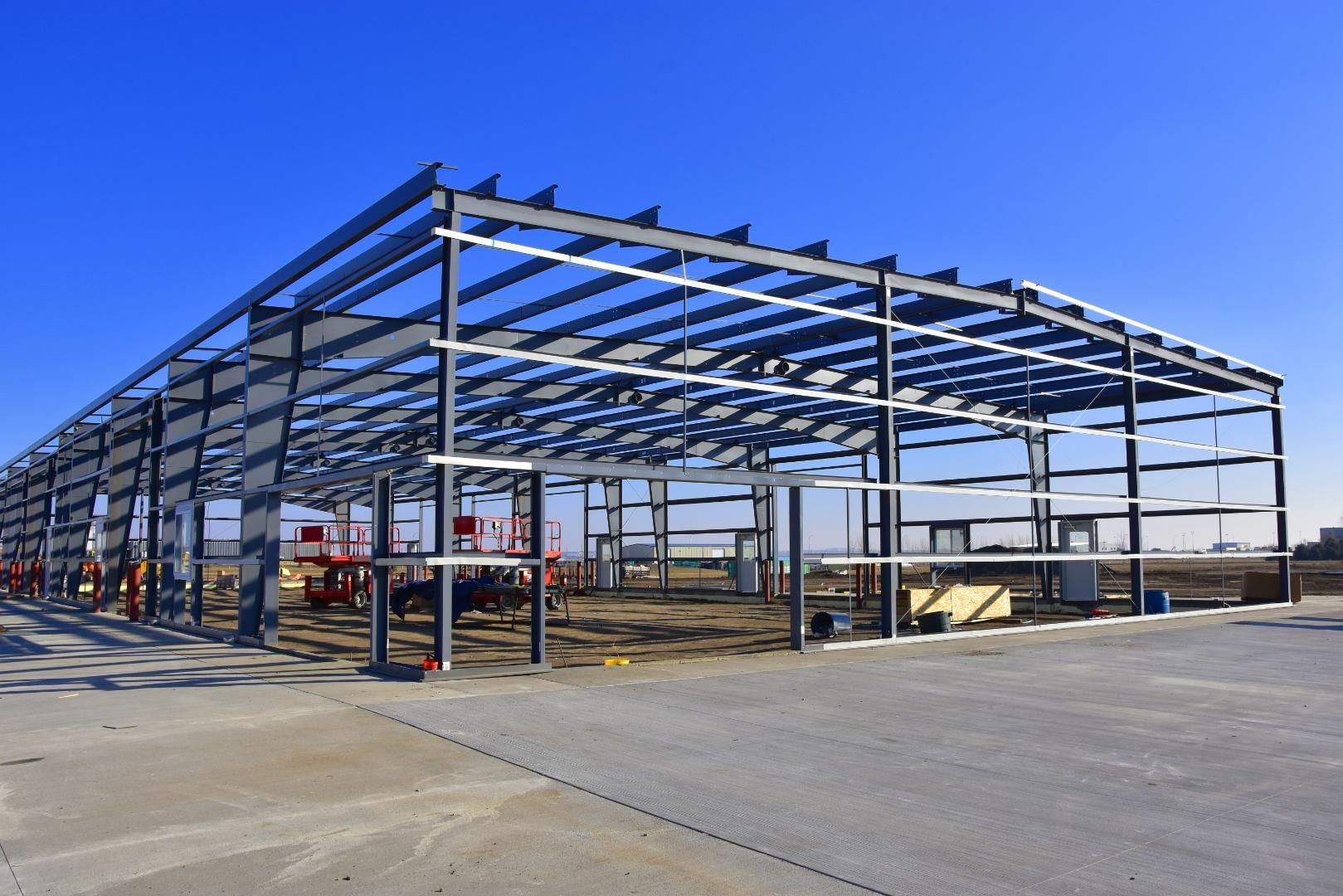 A large metal building under construction with a blue sky in the background.