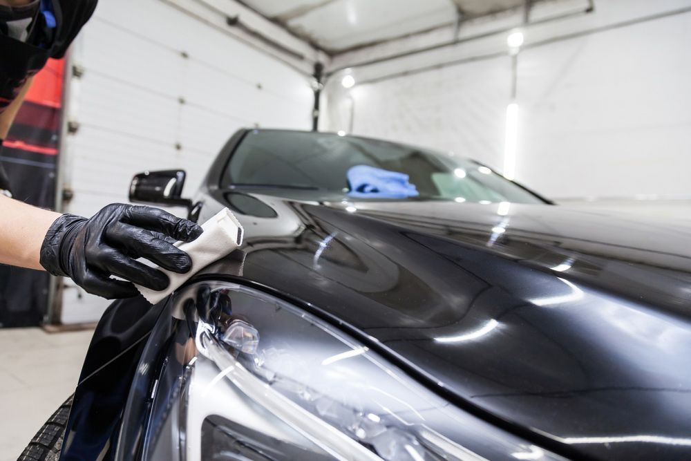 A Person Is Polishing A Black Car With A Cloth In A Garage — Tint a Car Sunshine Coast In Maroochydore, QLD
