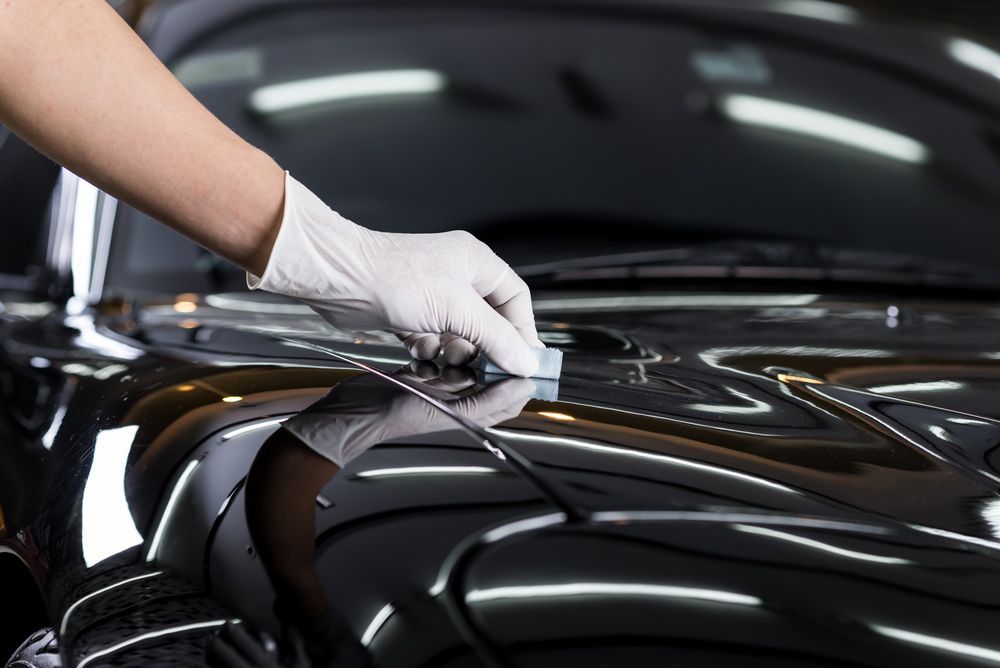 A Person Is Polishing The Hood Of A Black Car — Tint a Car Sunshine Coast In Maroochydore, QLD