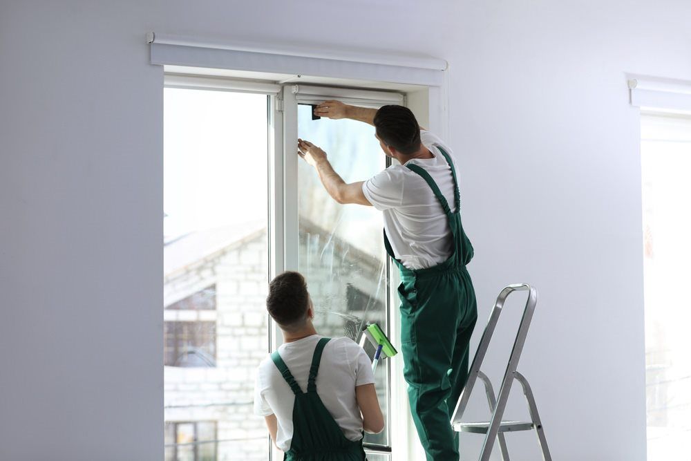 Two Men Are Cleaning A Window In A Room — Tint a Car Sunshine Coast In Buderim, QLD