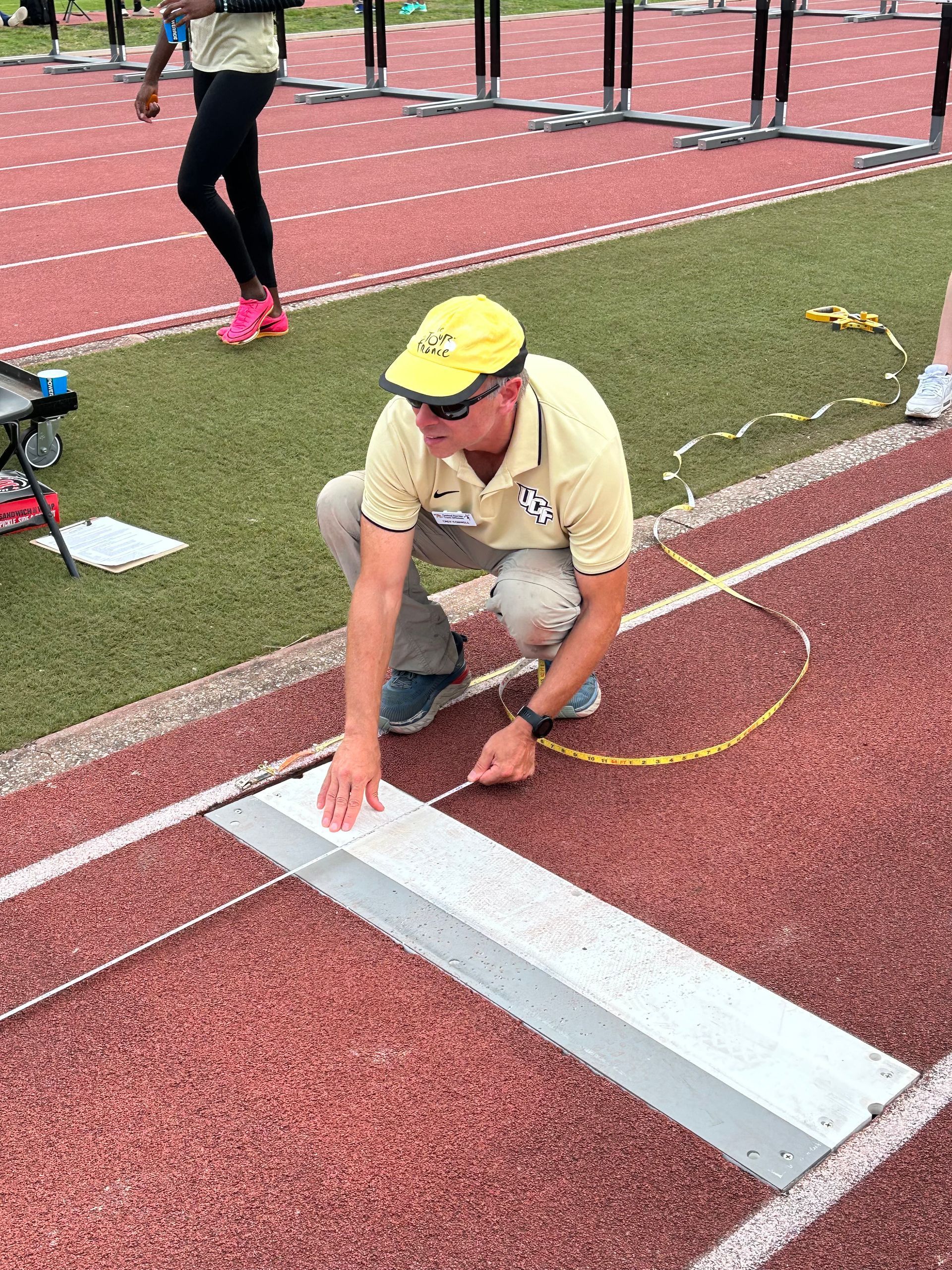 A man is measuring a track with a tape measure.