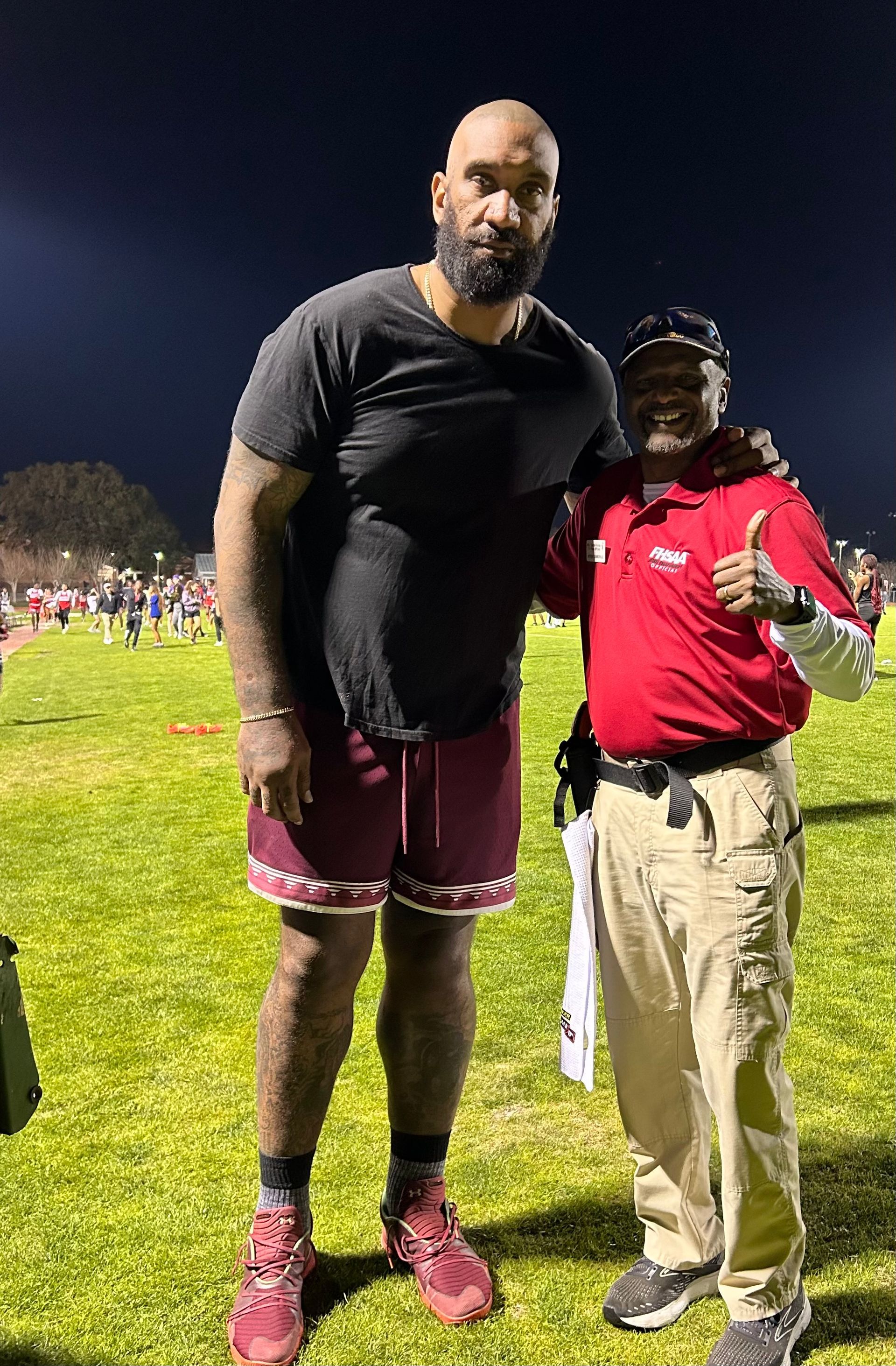 Two men are standing next to each other on a football field.