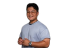 A man wearing glasses and a watch is standing in front of a white background.