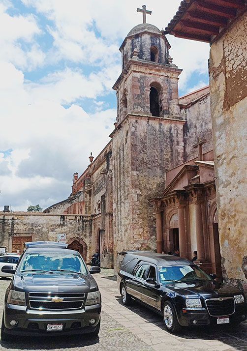 Hay una urna con flores y velas al fondo.