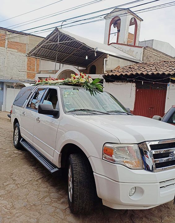 Hay una urna con flores y velas al fondo.