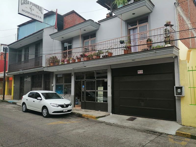 Hay una urna con flores y velas al fondo.