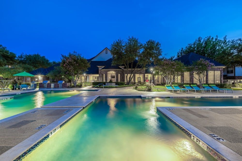 Night view of Marquis at Stonebriar's apartment resort-style swimming pool with lighting in Frisco, TX.