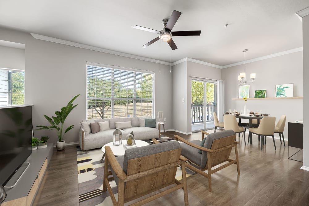 Modern living room seamlessly connected to a dining area with contemporary furniture, with neutral tones and natural light streaming in through the large windows at Marquis at Stonebriar in Frisco, TX. 