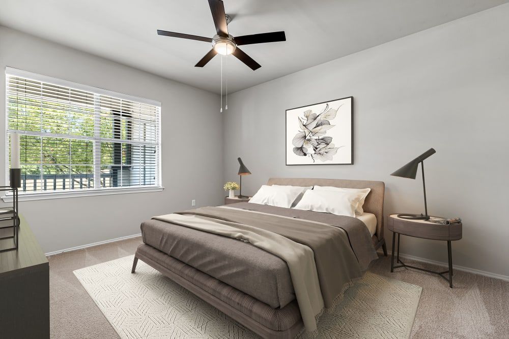 A modern and neatly decorated bedroom featuring a large bed with a tan upholstered headboard, white bedding, and a brown blanket at Marquis at Stonebriar in Frisco, TX.