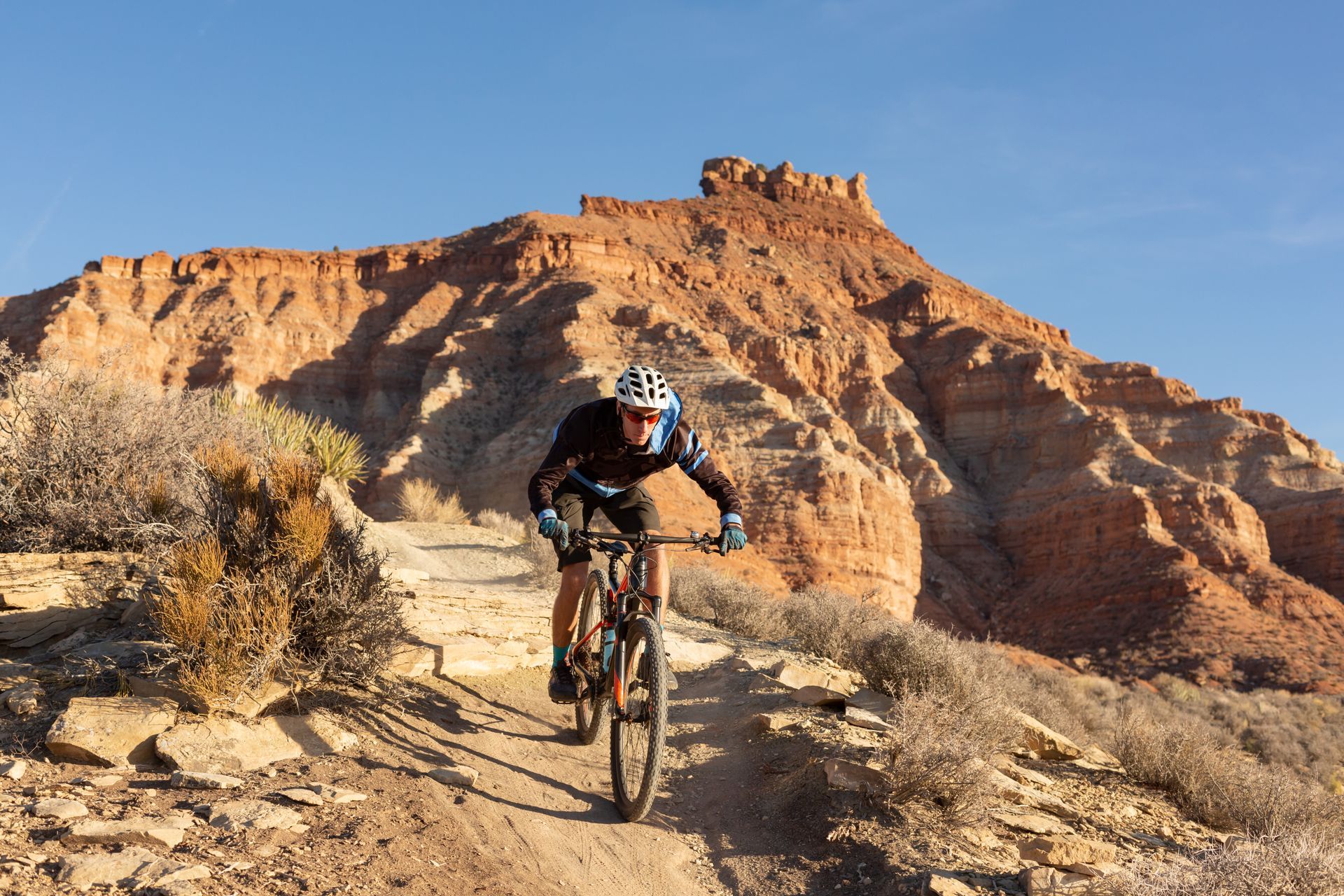 A man is riding a bike on a dirt trail in the desert.
