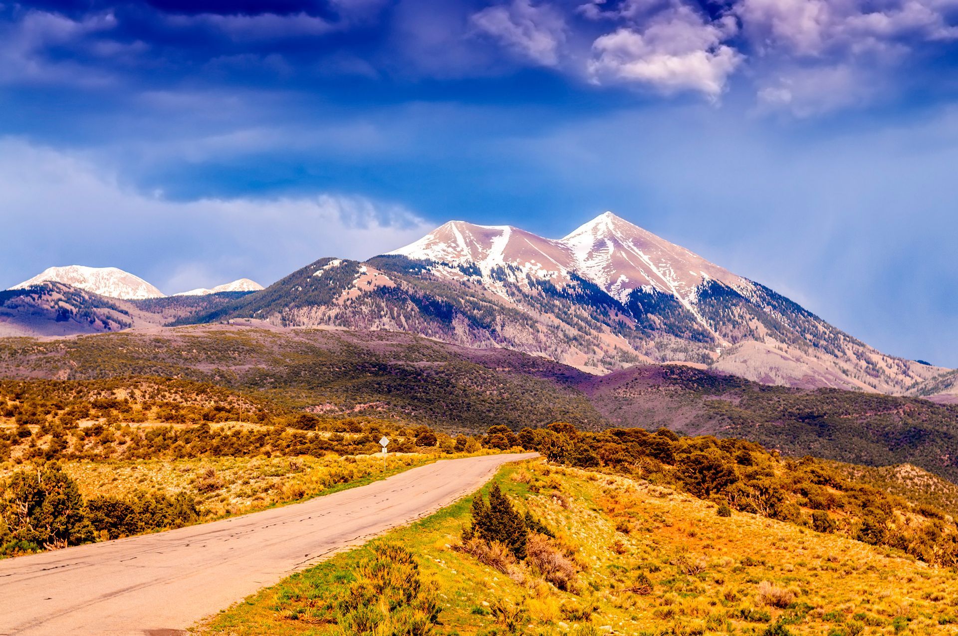 A dirt road going through a desert with mountains in the background.