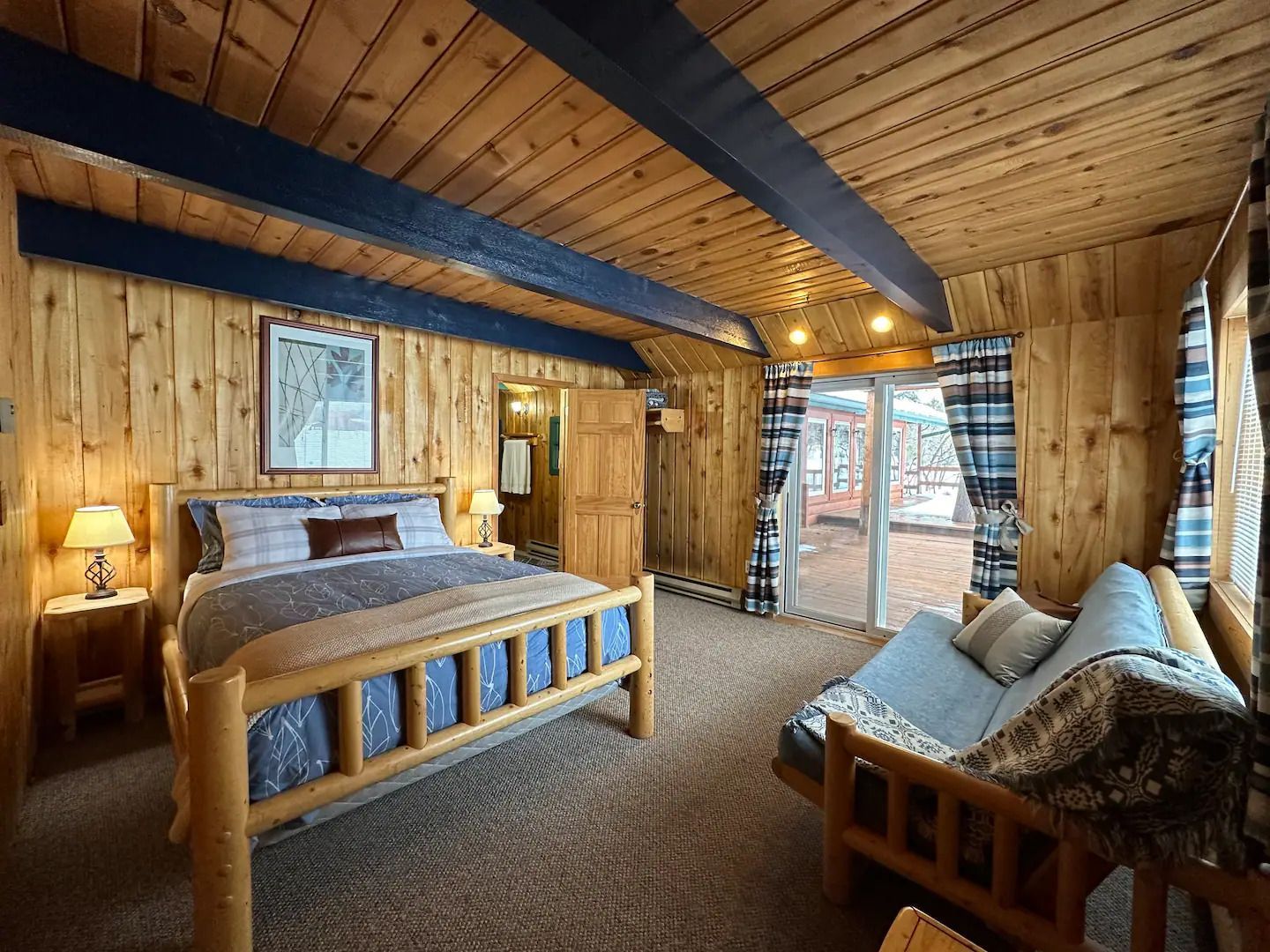 A bedroom with a log bed , couch , and sliding glass door.