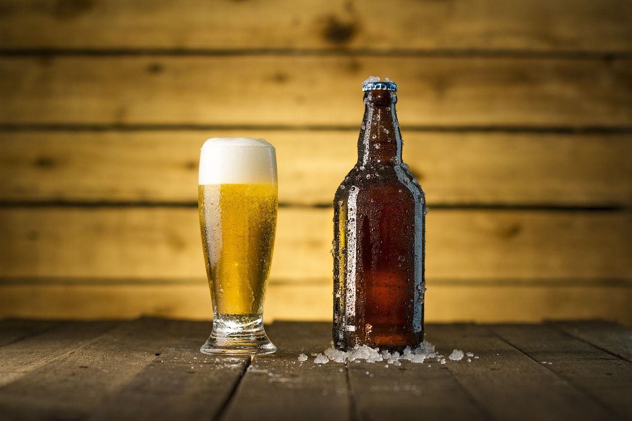 A bottle of beer and a glass of beer on a wooden table.
