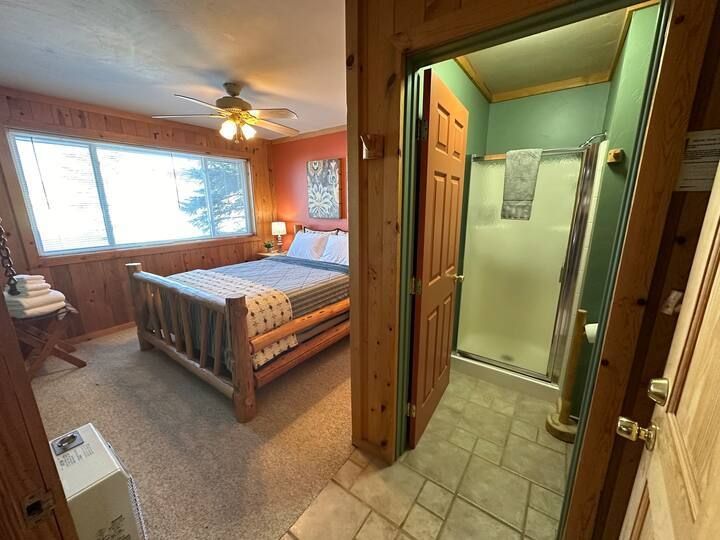 A bedroom with a king size bed and a walk in shower.