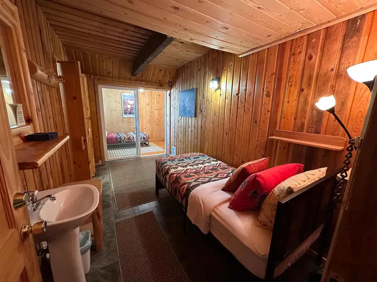 A bedroom with two beds , a sink and a mirror.