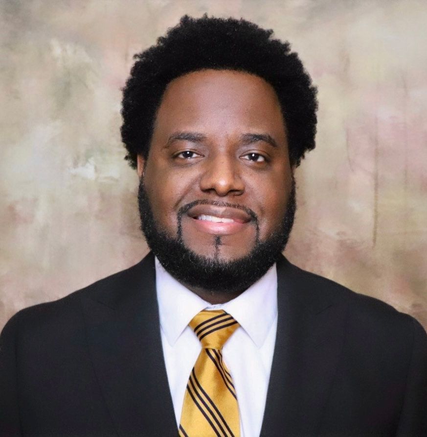 A woman in a gray jacket and black shirt is smiling for the camera.