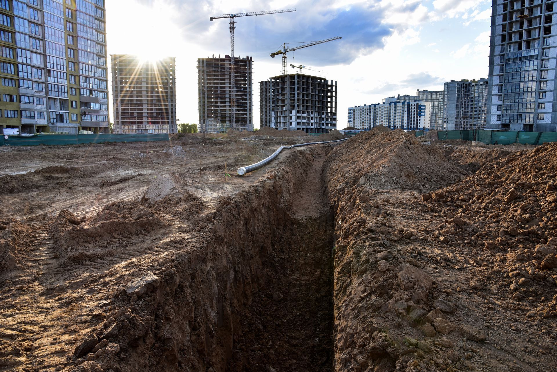 A construction site with a lot of dirt and buildings in the background.