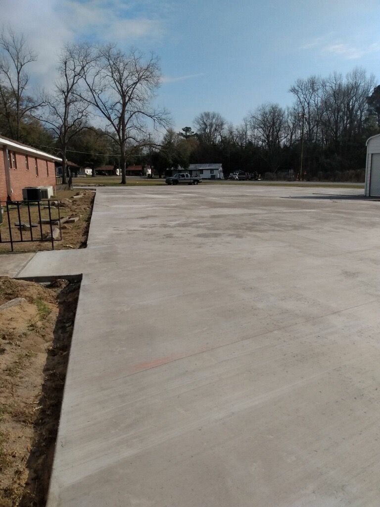 Tan stucco house with white porch and garage. Concrete driveway, green grass, blue sky.