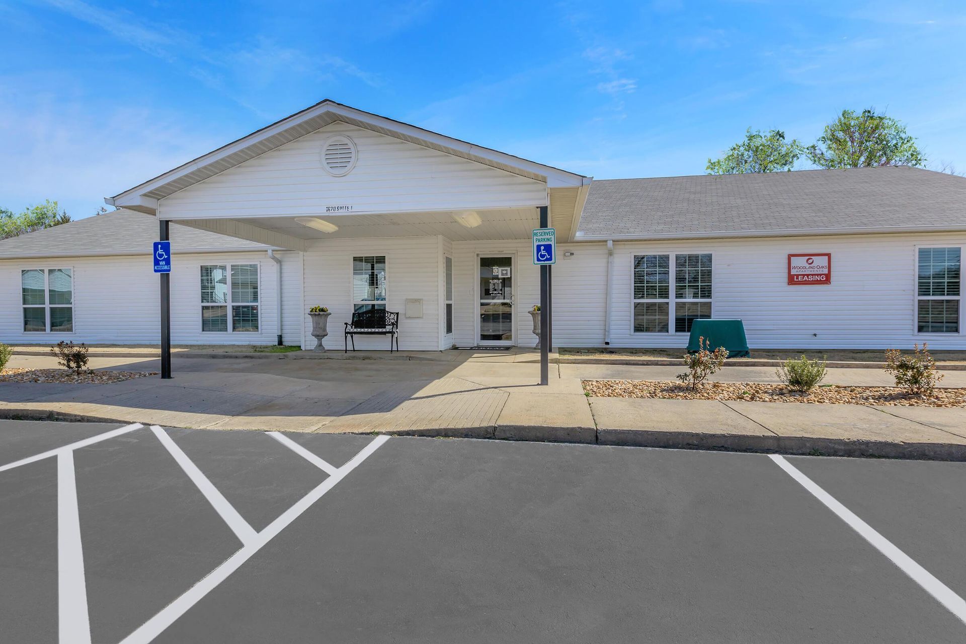 White single-story building with a covered entrance and accessible parking spaces. Blue sky.