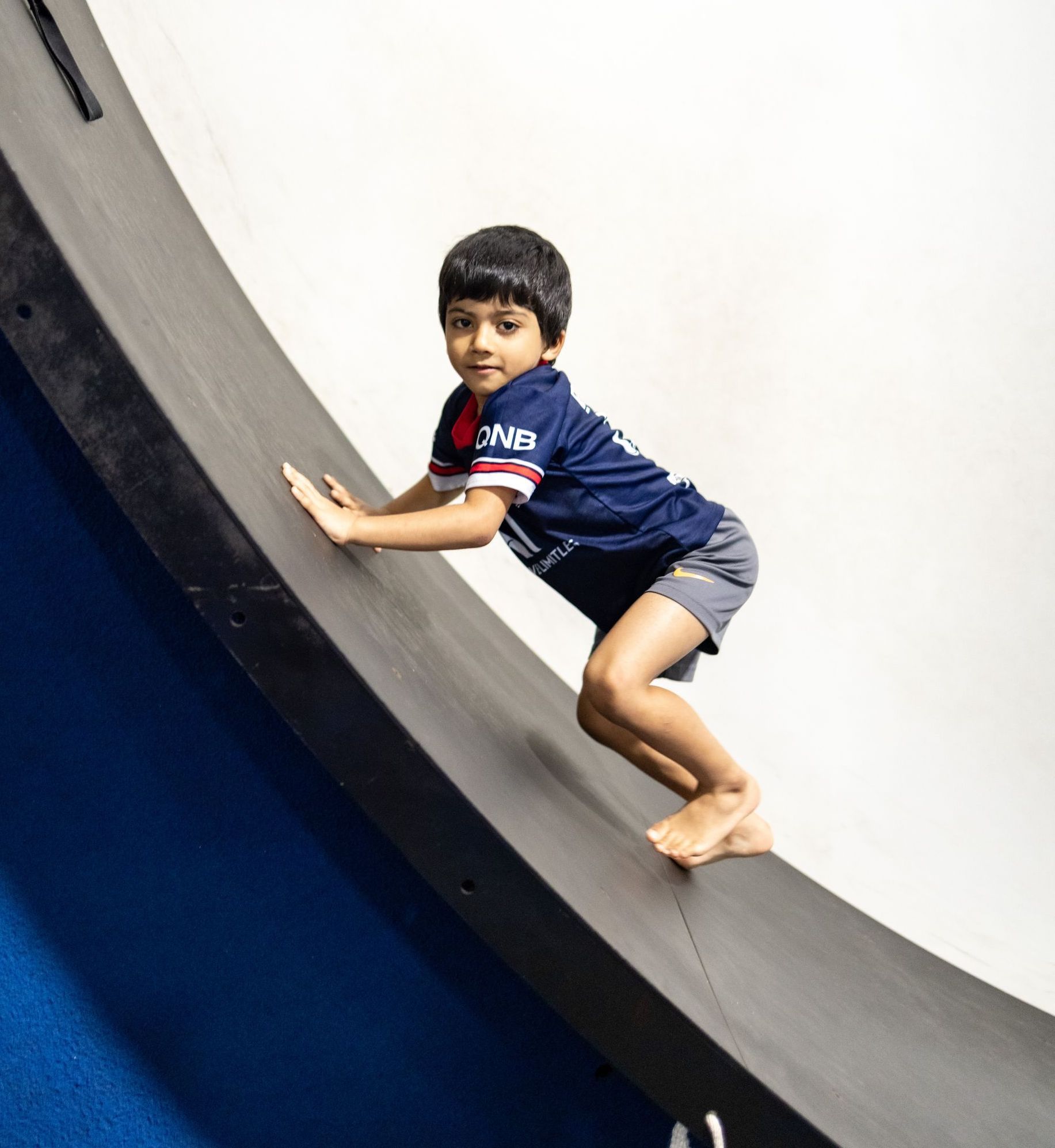 A young boy wearing a shirt that says cnr is playing on a slide