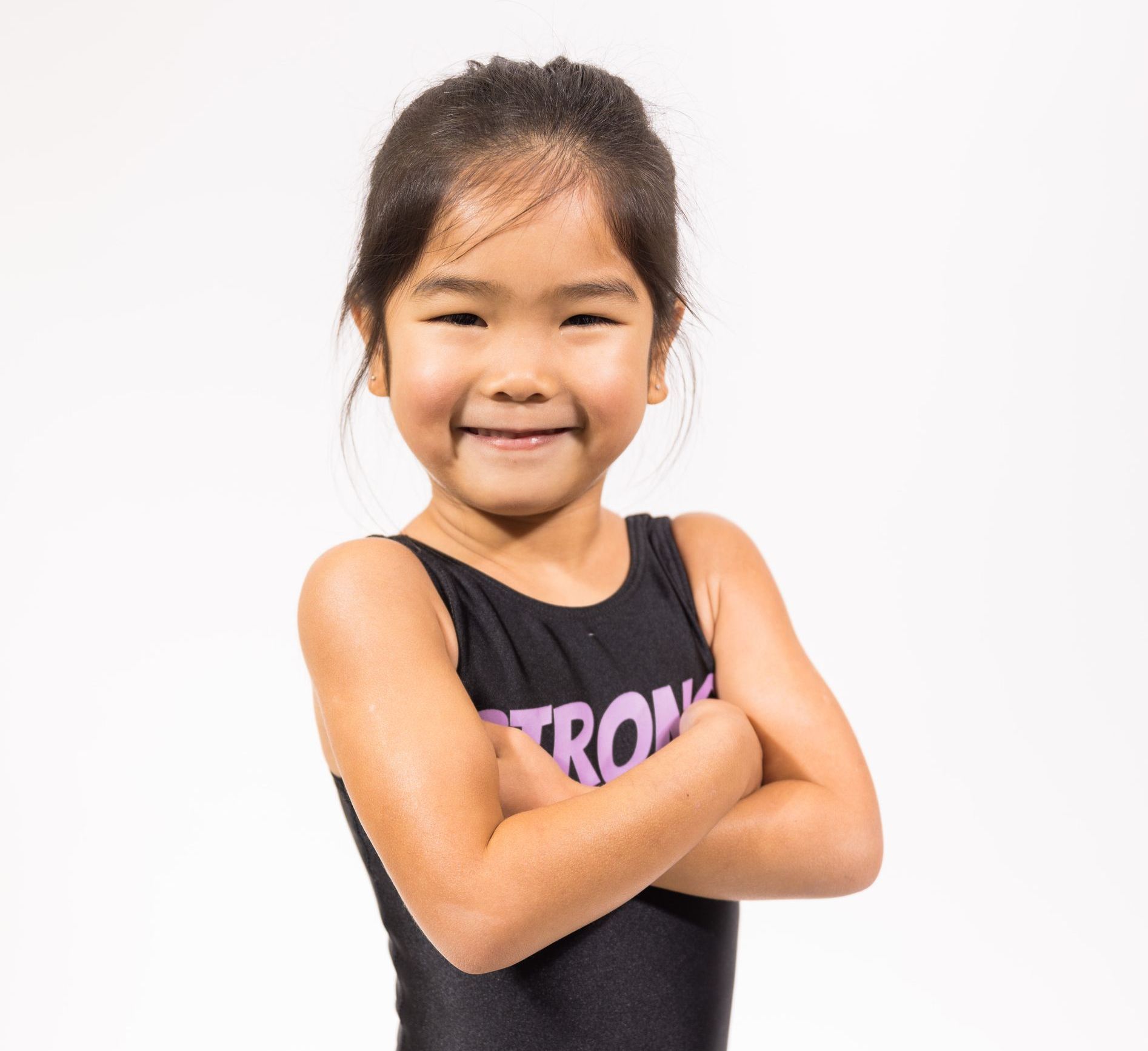 A little girl in a black tank top with the word strong on it