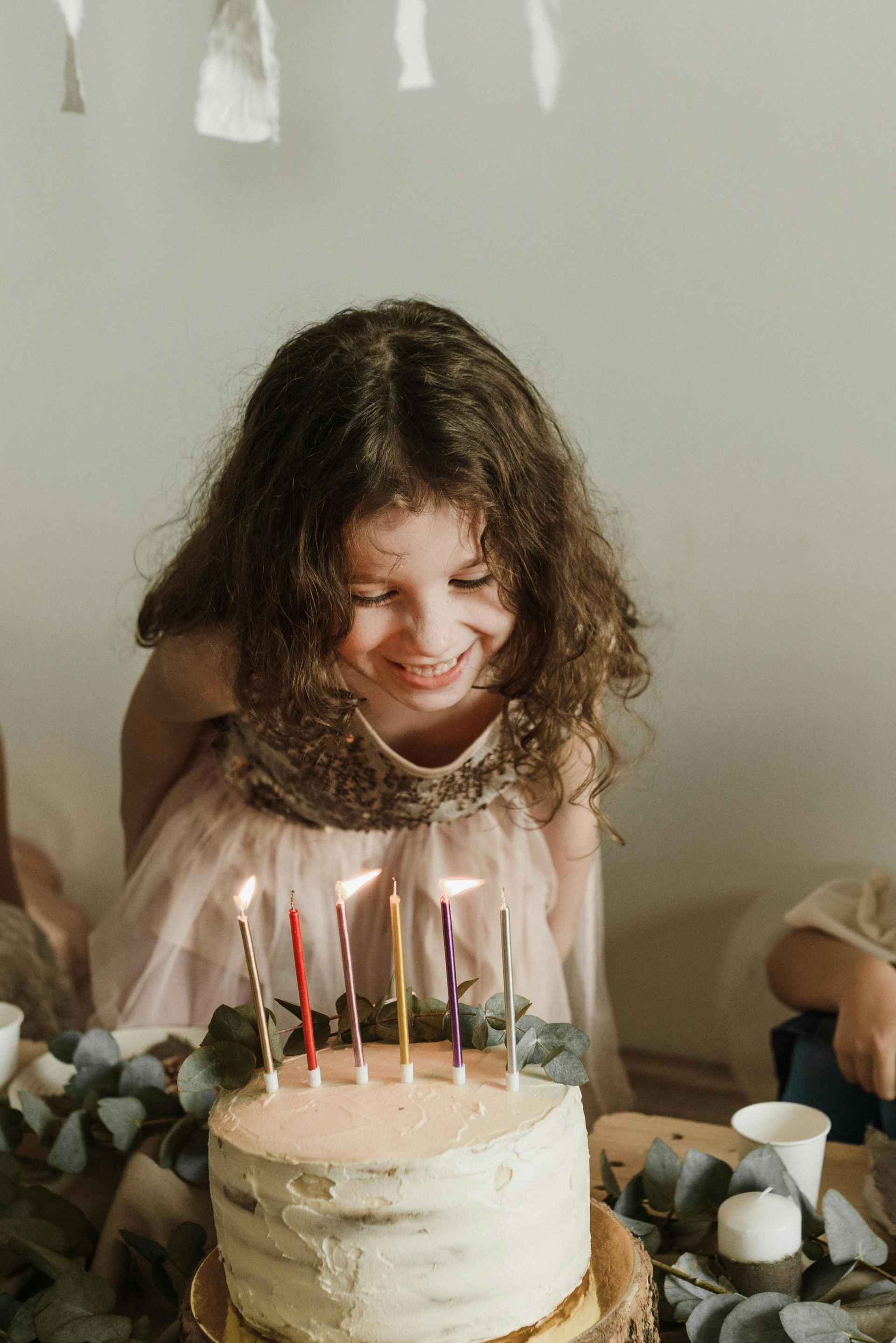 A little girl is blowing out candles on a birthday cake.