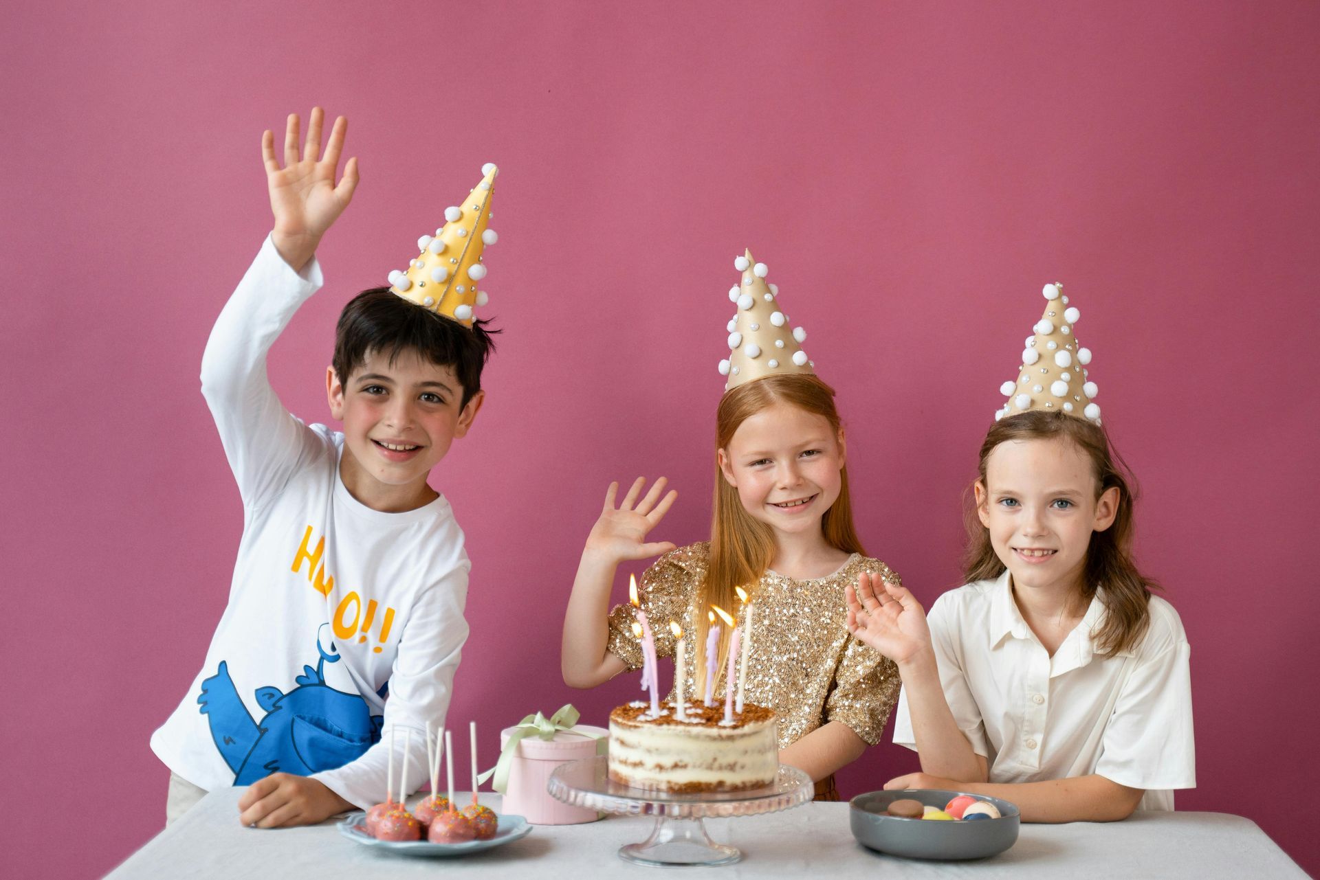 A group of children are sitting at a table with a birthday cake.