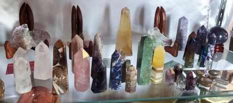 Various colorful crystals arranged on a glass shelf, possibly for sale.