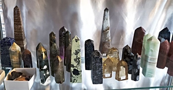 Collection of varied, tall, polished crystals on display, with neutral backdrop.