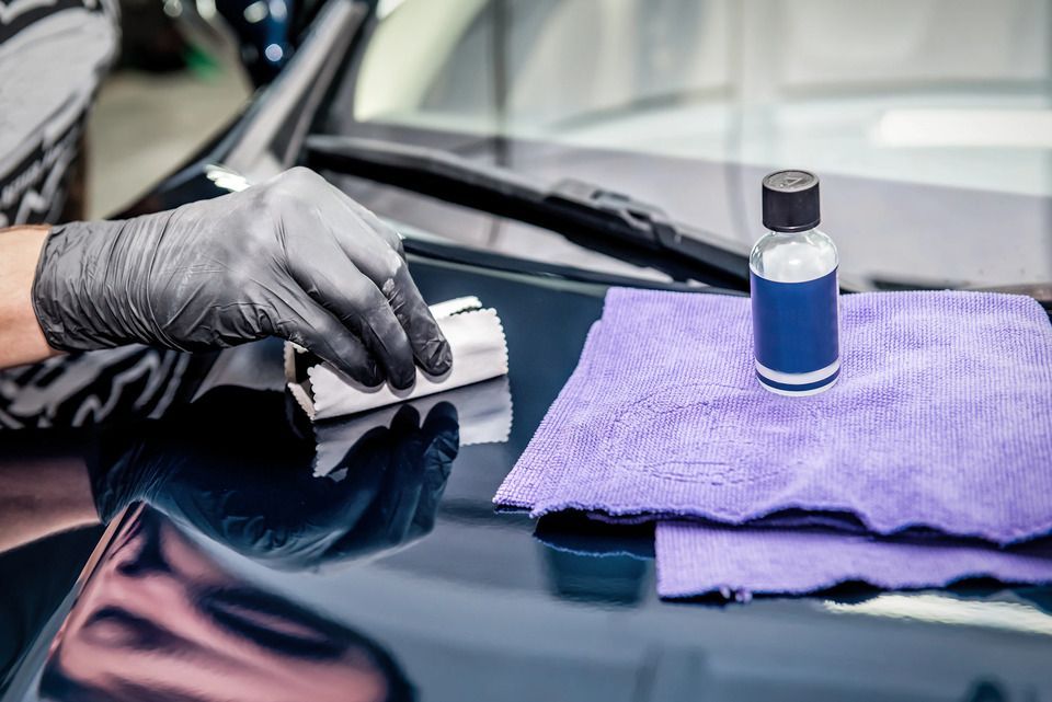 A person is applying a coating to the hood of a car.