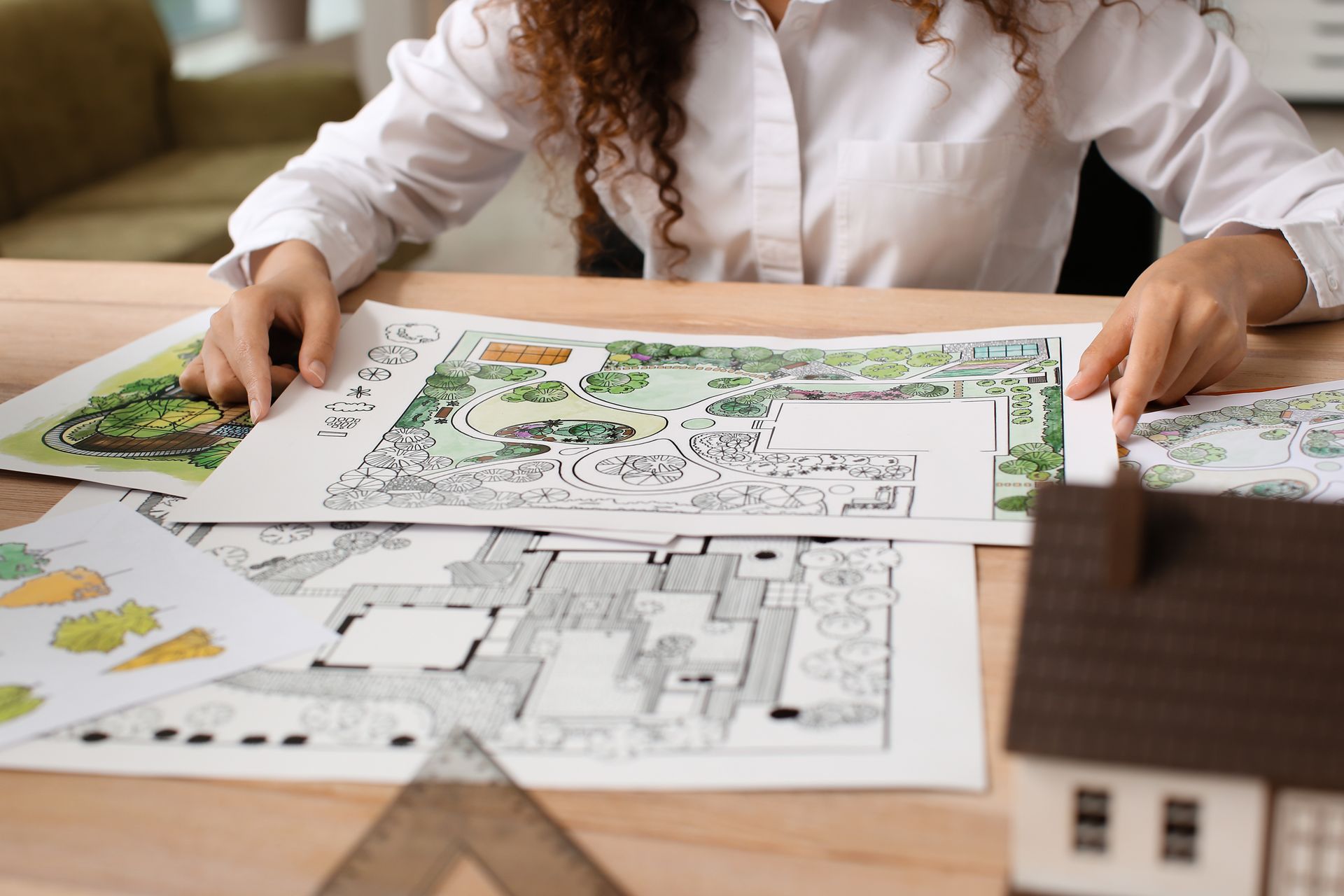 A woman is sitting at a table looking at a drawing of a house.