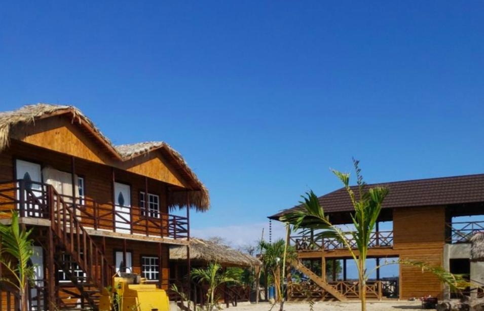 A group of wooden houses with thatched roofs on a beach.