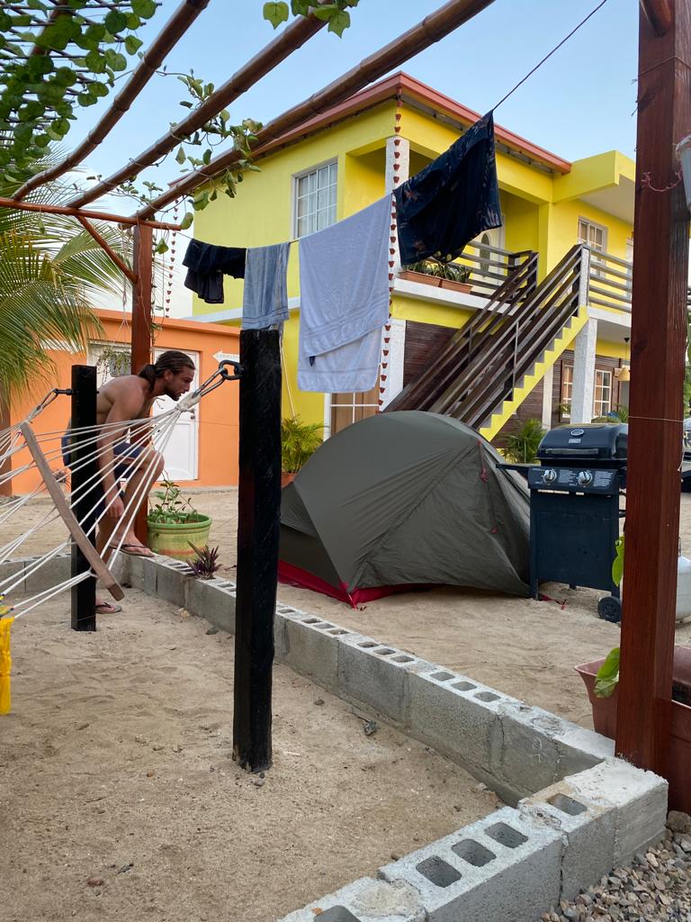 A man in a hammock in front of a yellow house