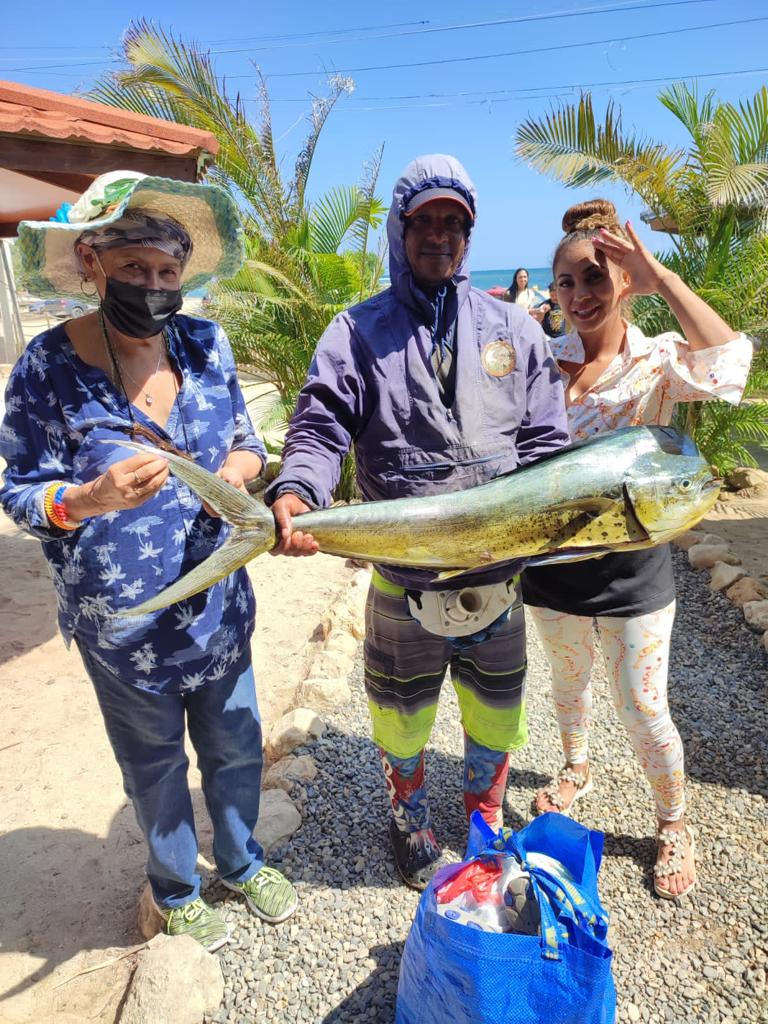 A man and two women are standing next to each other holding a large fish.