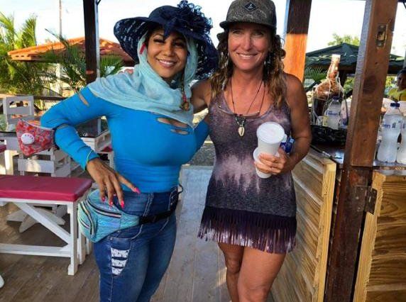 Two women are posing for a picture and one is wearing a hat