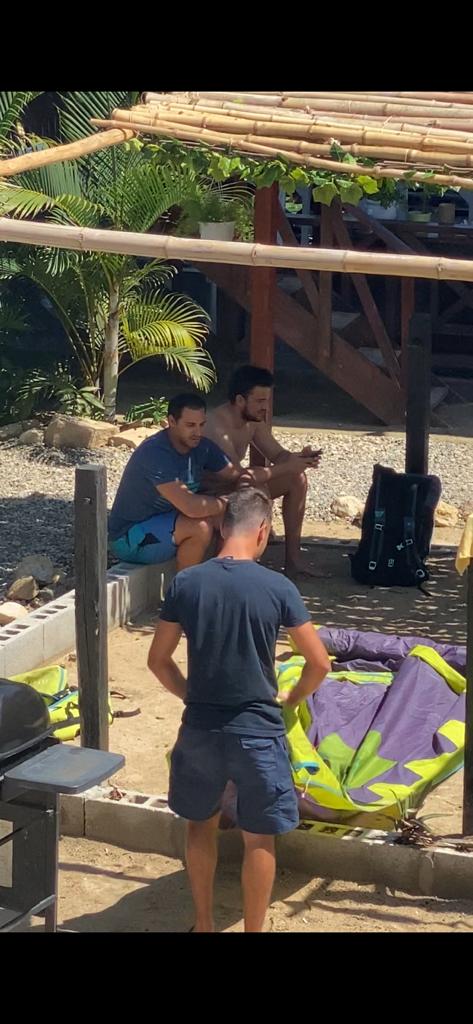 A group of men are sitting on a bench on the beach.
