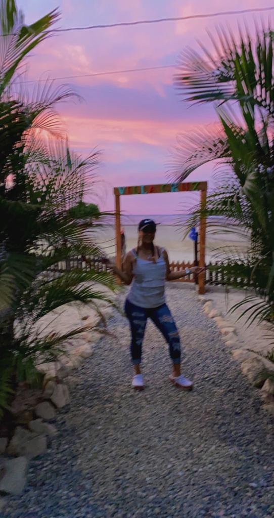 A woman is standing in front of a beach at sunset.