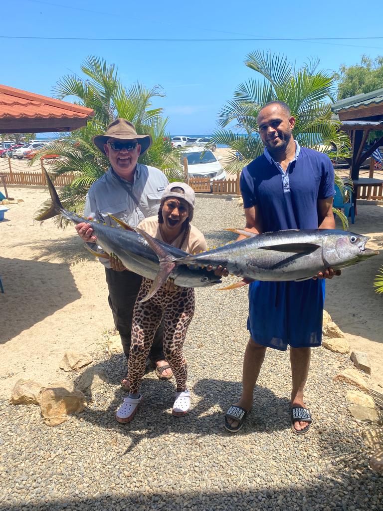 Three people are standing next to each other holding a large fish.
