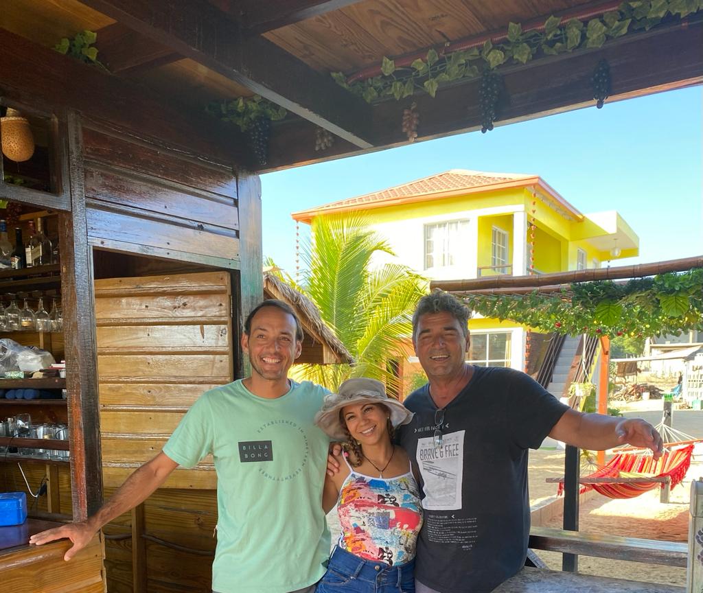 Three people posing for a picture in front of a wooden building