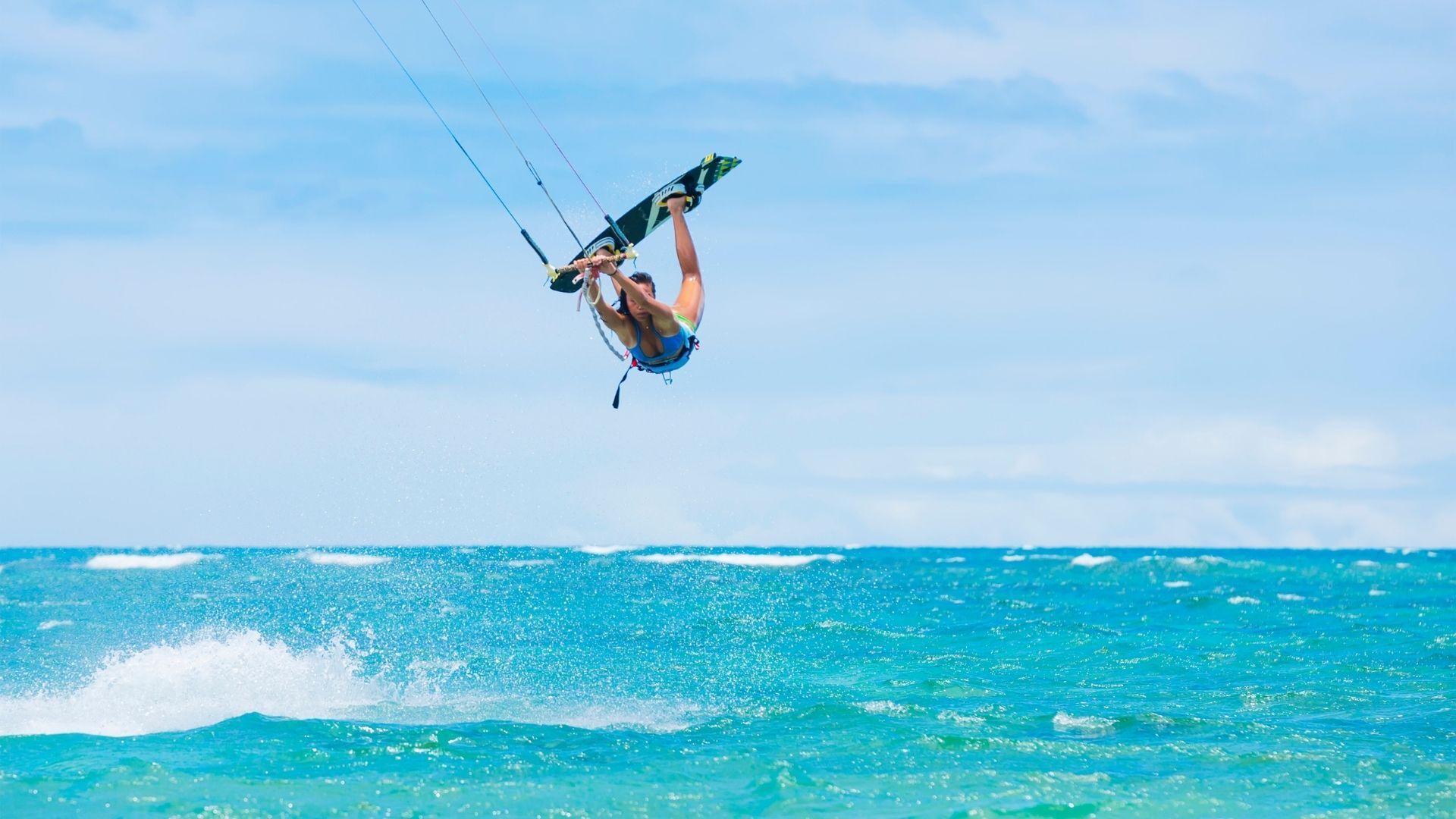 A man is flying through the air while kitesurfing in the ocean.