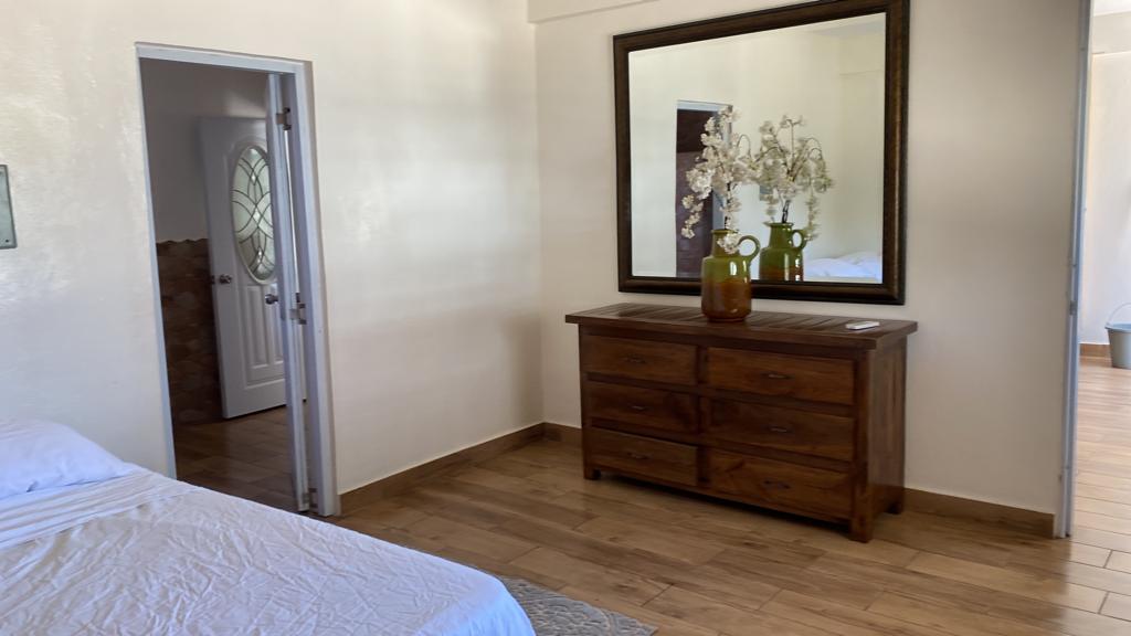 A bedroom with a bed , dresser and mirror.