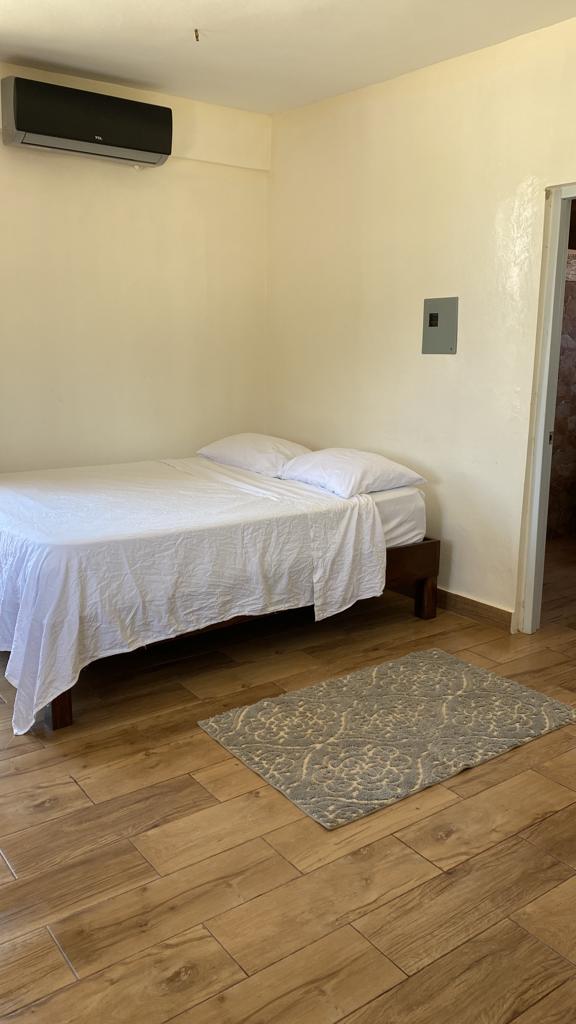 A bedroom with a bed and a rug on the floor.